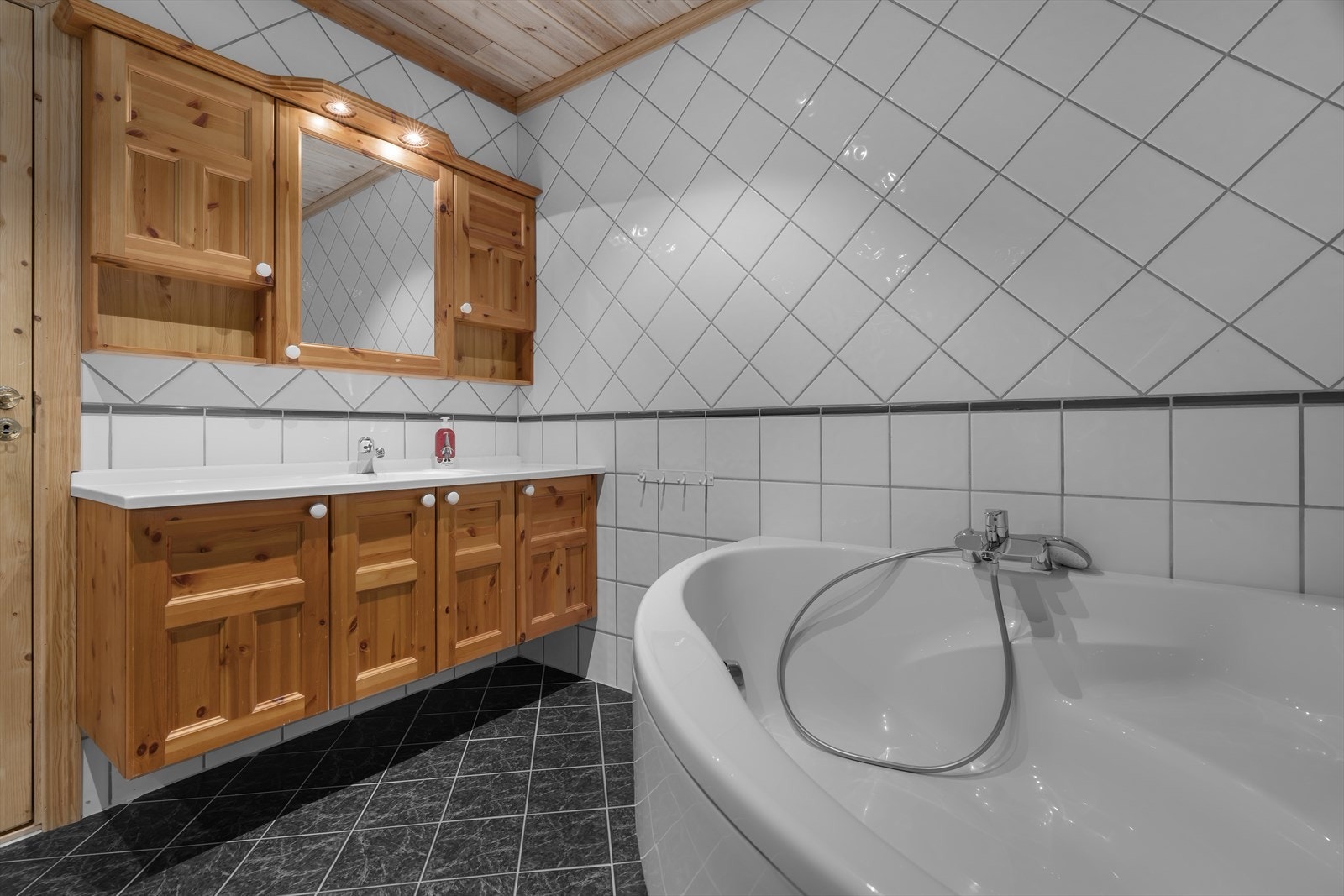 Flislagt med varmekabler, innredet med hjørne badekar, dusj, servant og toalett. Galleribilde