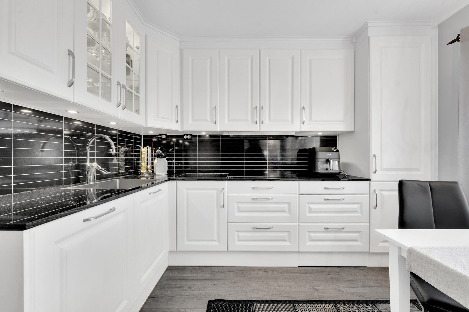 Innredning med profilerte fronter, integrerte hvitevarer og benkeplate av stein. Galleribilde