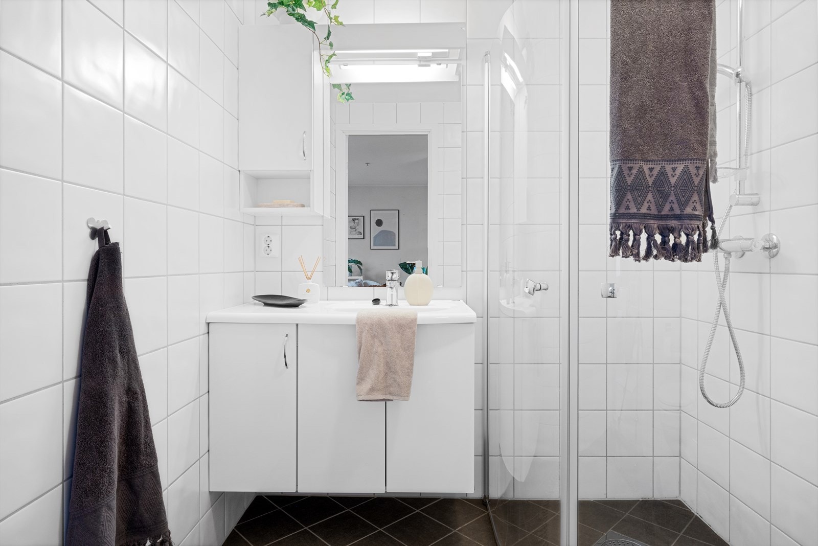 Badet er innredet med servant i møbel, vegghengt toalett og dusj med glassdører. Varmekabler i gulv. Galleribilde