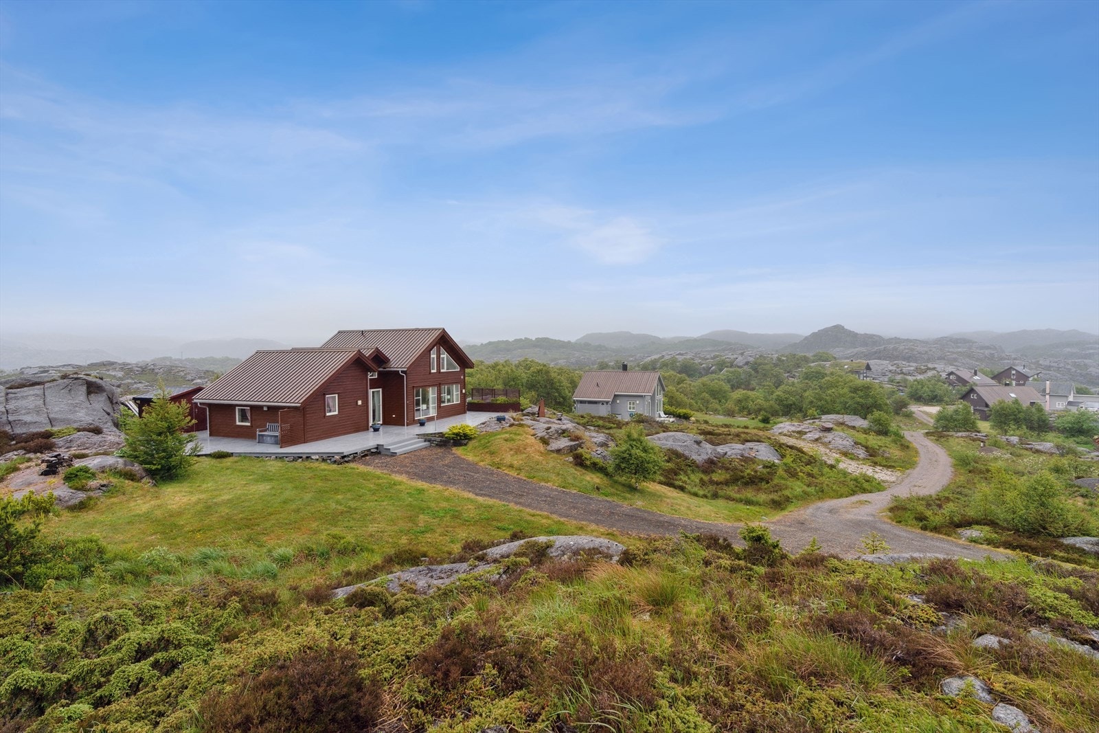 Tomten ligger i kystterreng opparbeidet med utvendige terrasser og hage/plen. Galleribilde