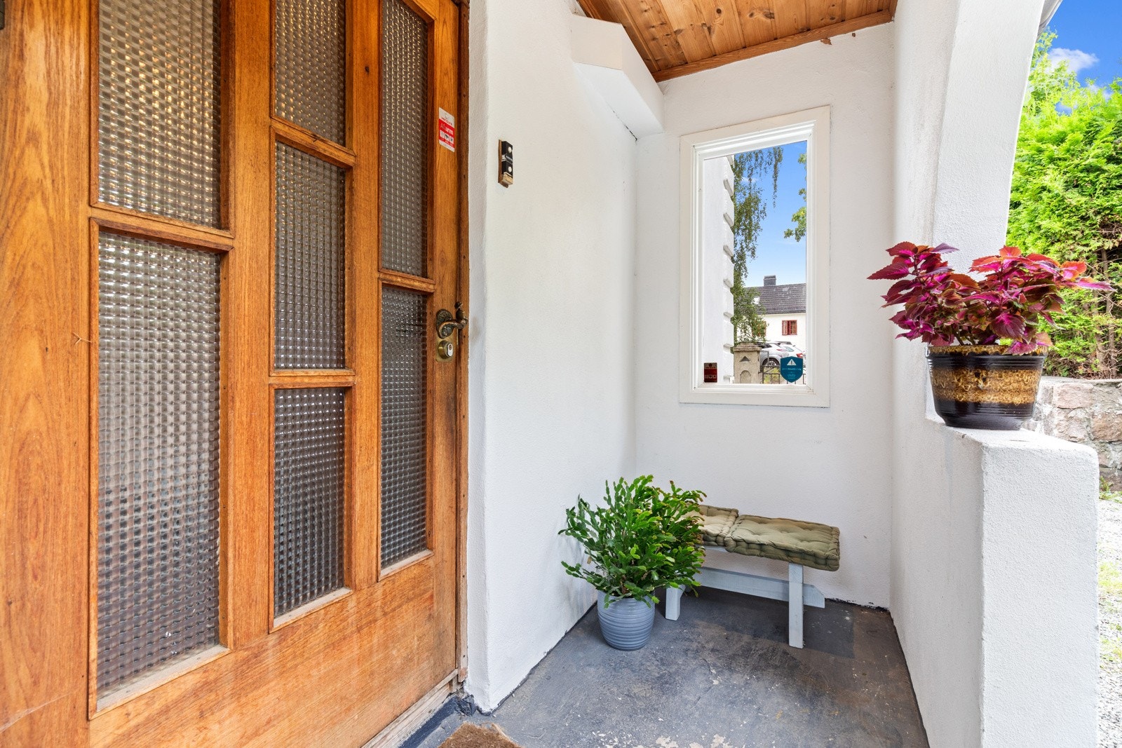 Overbygget inngangsparti med vinduer og sitteplass. Galleribilde