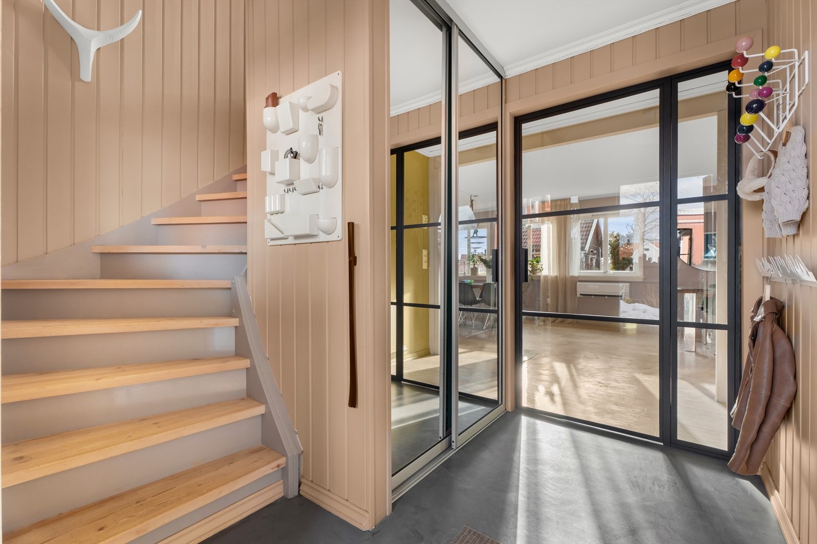 Fra gangen leder trappen opp til andre etasje, og en glassdør åpner inn mot stuen. Galleribilde