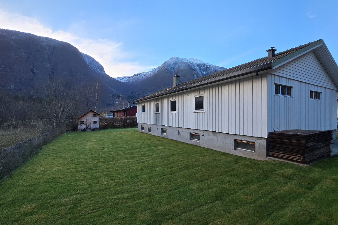 Dette bilde er redigert med KI, og er bere meint som ein illustrasjon av korleis hage kan sjå ut ved ryddig og opparbeiding av plen. NB: Kjellar-inngongen frå hagen er borte på dette bilde, og detaljar på huset kan avvike frå reell tilstand. Galleribilde