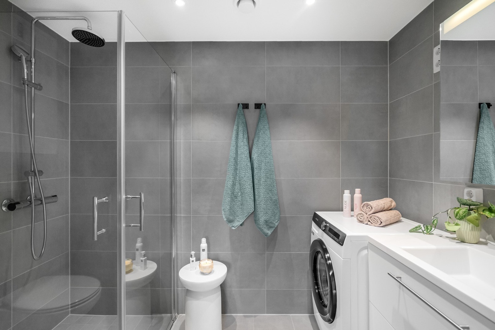 Badet fremstår som moderne og stilrent, med flislagte vegger og gulv i tidløse gråtoner. Galleribilde