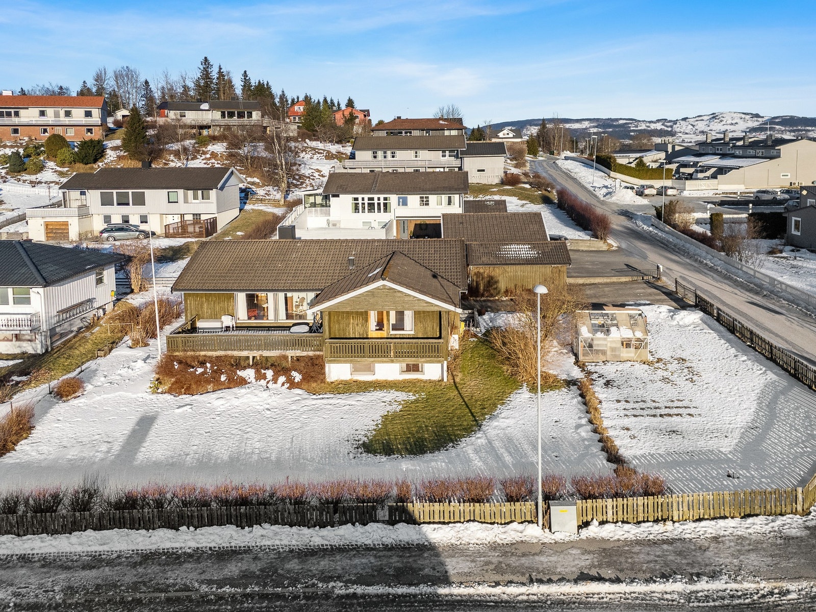 Asfaltert gårdsplass. Bordkledning er av impregnert materiale. Galleribilde