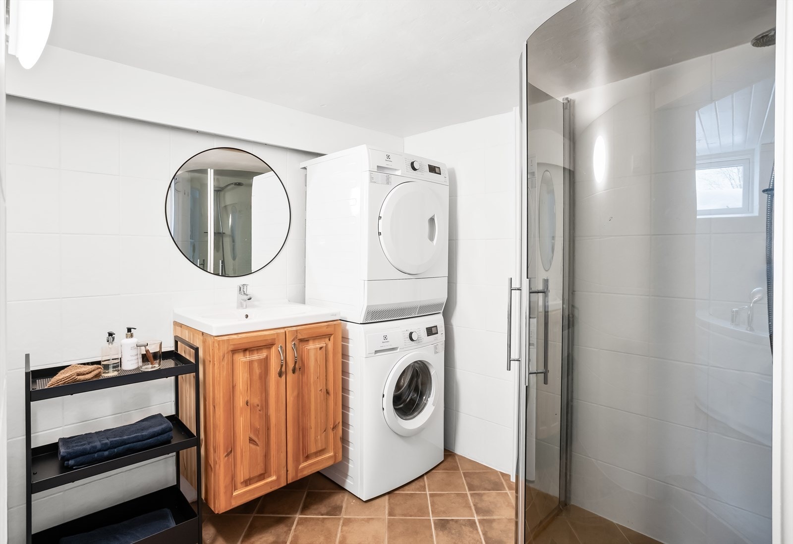Badet har servant med speil, dusjhjørne og opplegg for vaskemaskin. Galleribilde