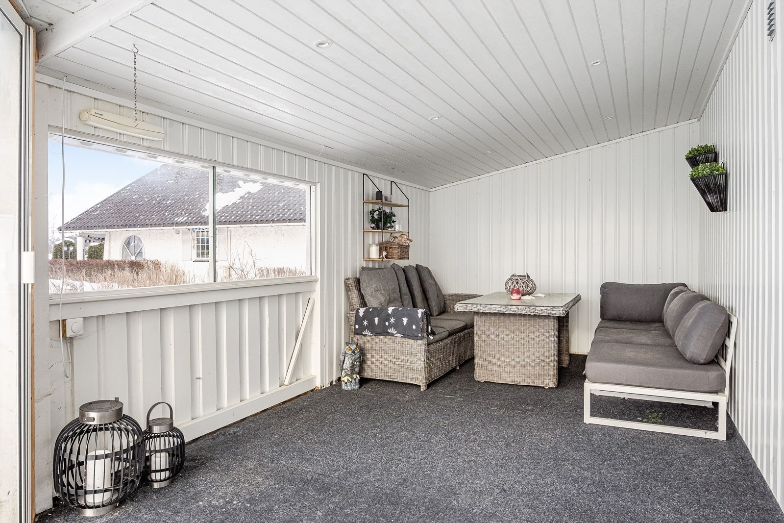 Dels innglasset veranda med teppebelagt gulv og trepanel på vegger gir et lunt uterom. Galleribilde