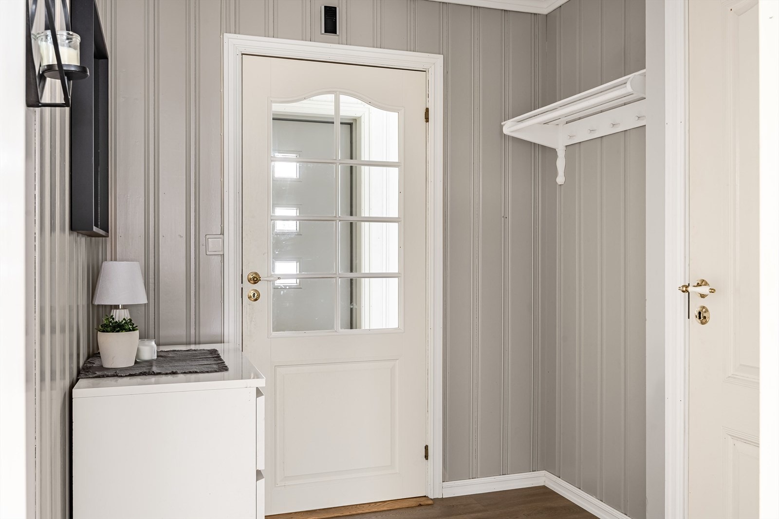 Videre kommer du inn til gang som har laminat på gulvet og trepanel på veggene malt i en lys grå farge. Galleribilde