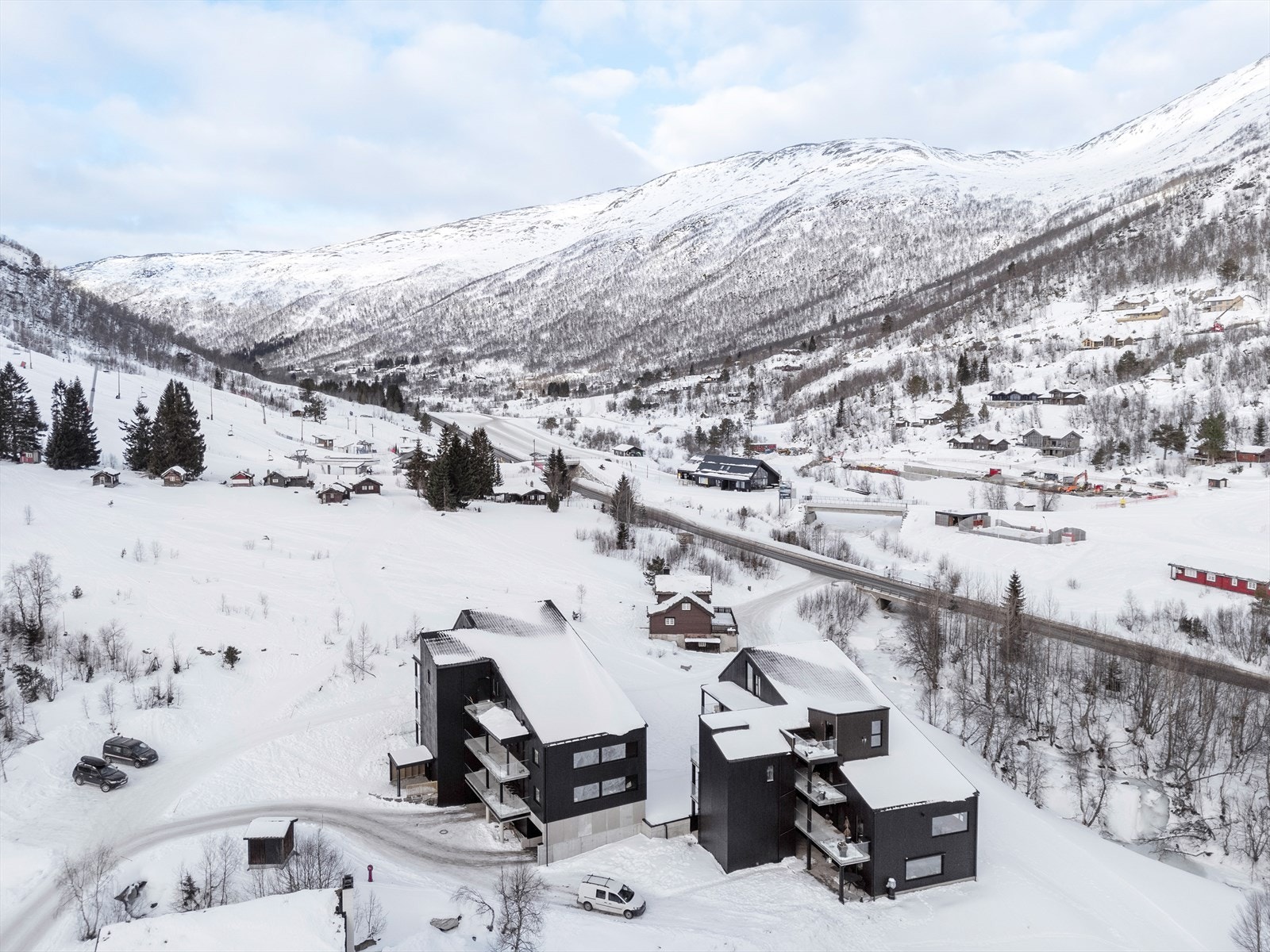 Bygget har en moderne arkitektur med mørk fasade som kontrasterer vakkert mot snøen. Galleribilde