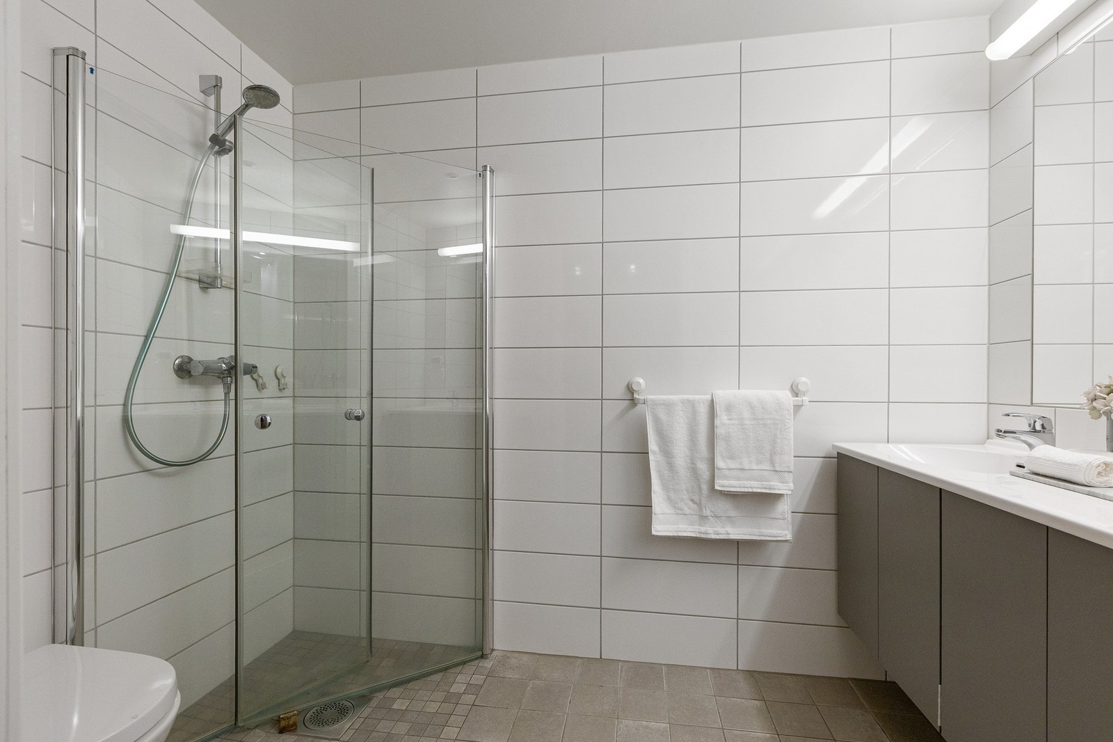 Videre er det adkomst til en-suite bad som er moderne og stilrent utført med flislagte overflater. Galleribilde