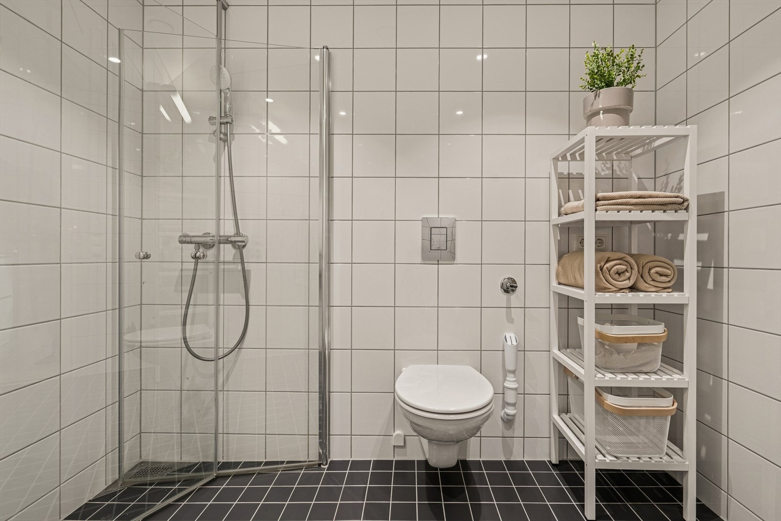 Rommet har opplegg for vaskemaskin, samt plassbesparende innfellbare dusjdører i glass. Galleribilde