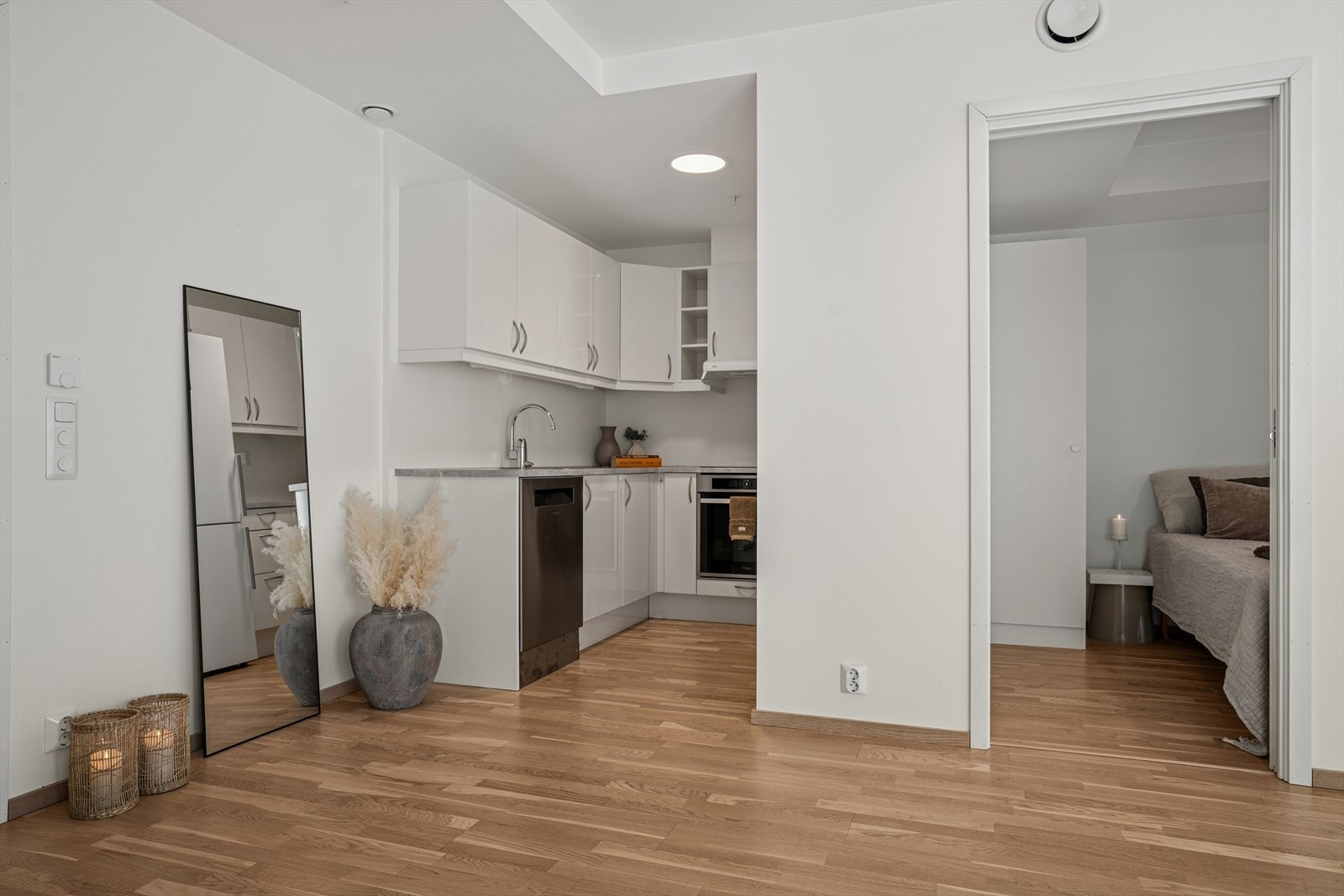 Kjøkkeninnredningen har tidløse fronter i slett, hvit utførelse, fliser under overskap og benkeplate med nedfelt servant. Galleribilde