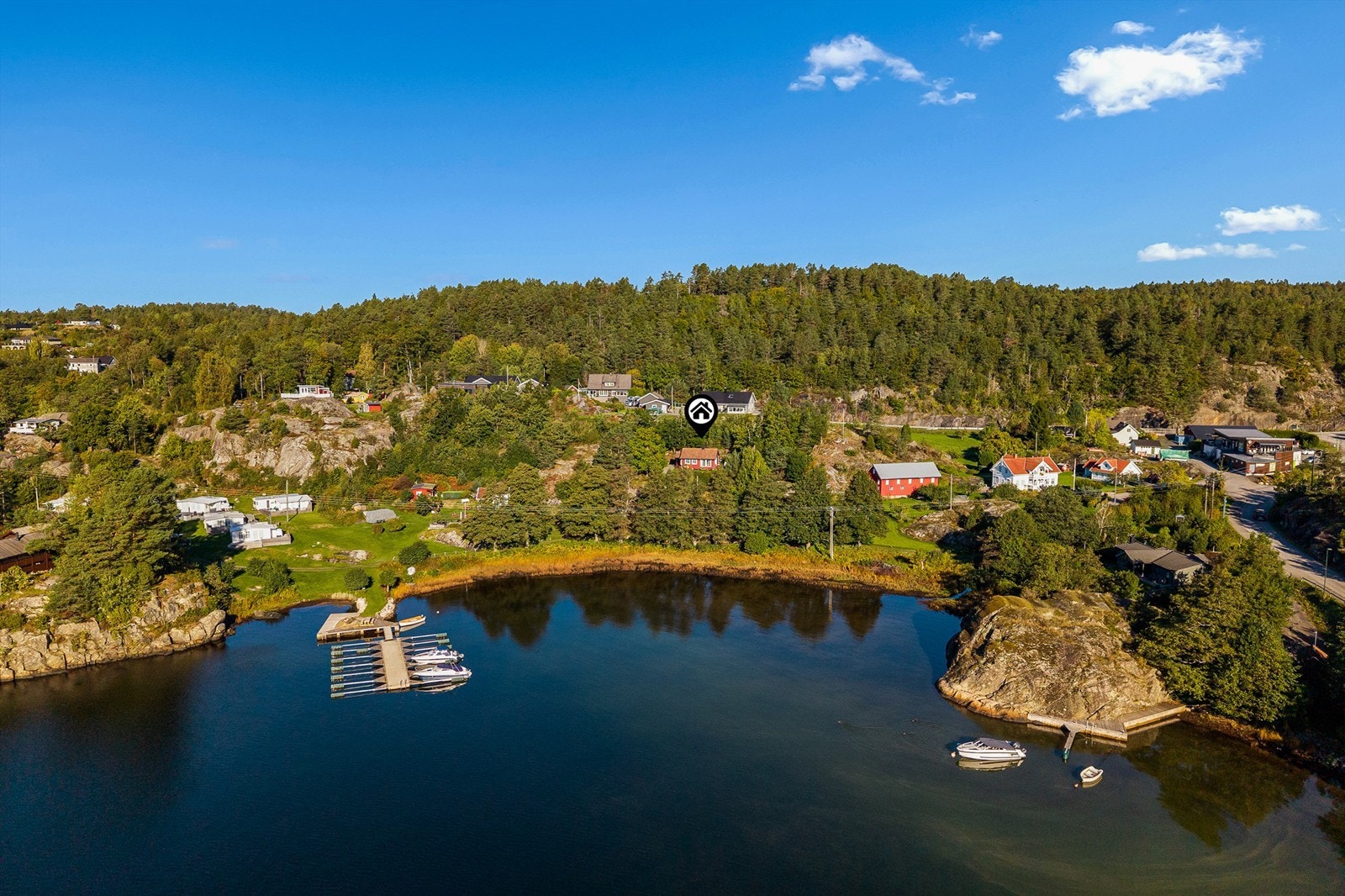 Kyststien går langs sjøen rett nedenfor og dagligvarebutikken i området ligger bare noen få minutters gange fra hytta. Den sees til høyre i bildet. Galleribilde