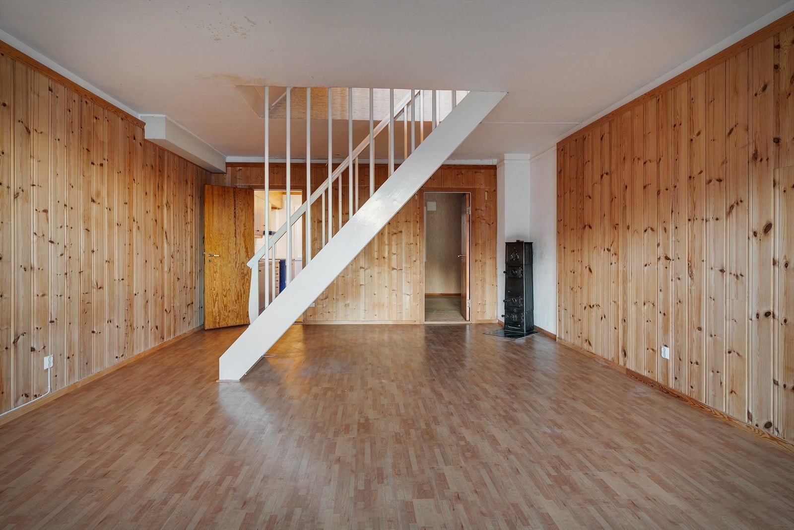 Vedovn av stål gir god varme i stuen. Her er også inngang til kjøkkenet og det tredje soverommet i leiligheten Galleribilde