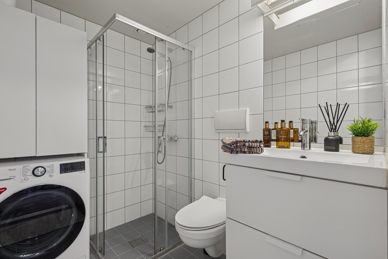 Videre inneholder badet et veggmontert toalett og dusjhjørne. Det er også opplegg for vaskemaskin. Galleribilde