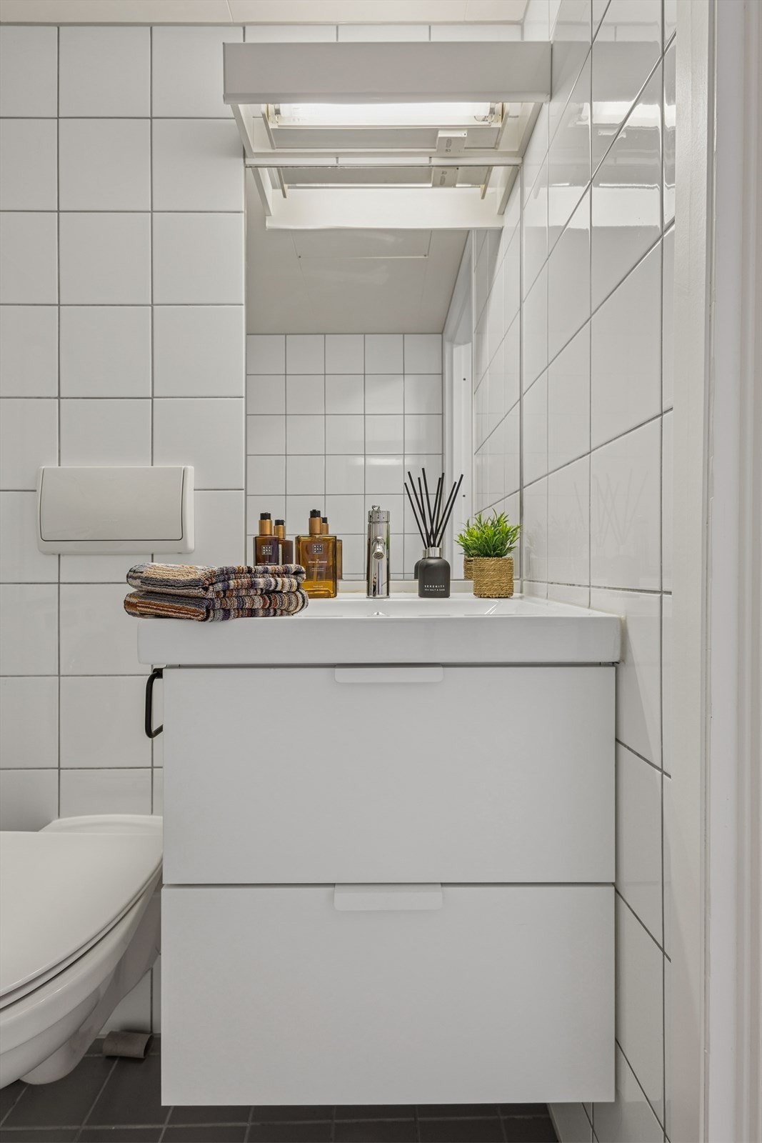 Badet har en hvit baderomsinnredning med heldekkende servant, samt speil med tilhørende belysning. og speil gir praktisk oppbevaring på badet. Galleribilde