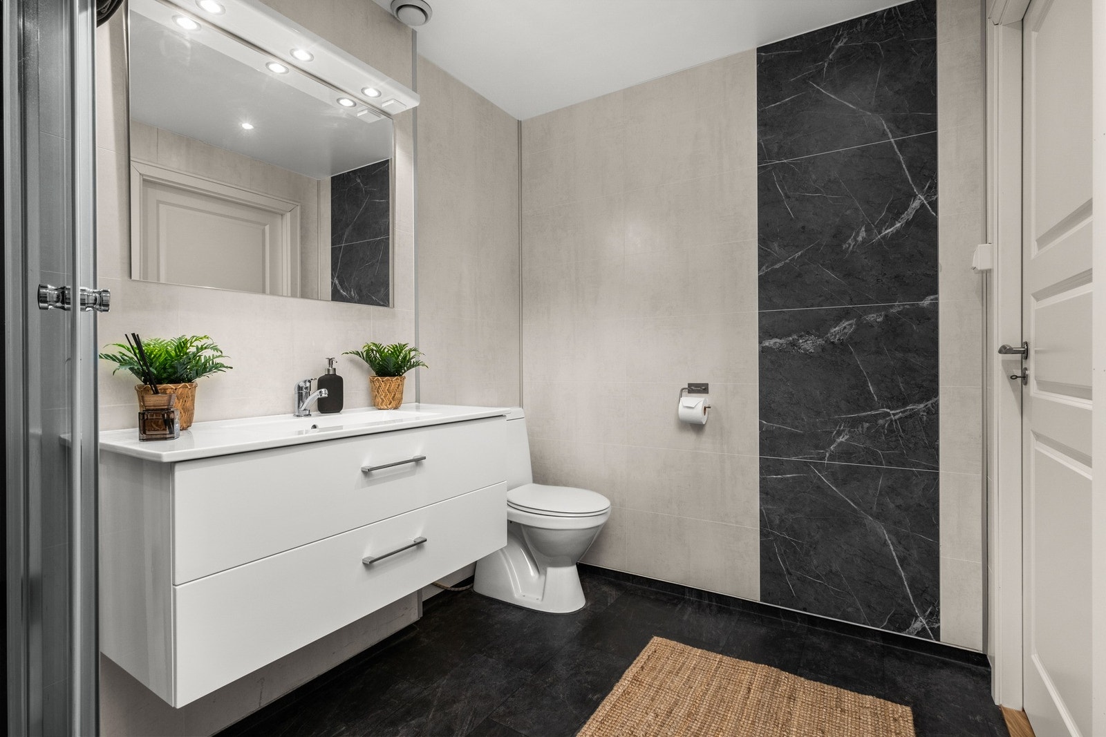 Badet er utstyrt med gulvmontert toalett, vegghengt innredning med servant og dusjkabinett Galleribilde