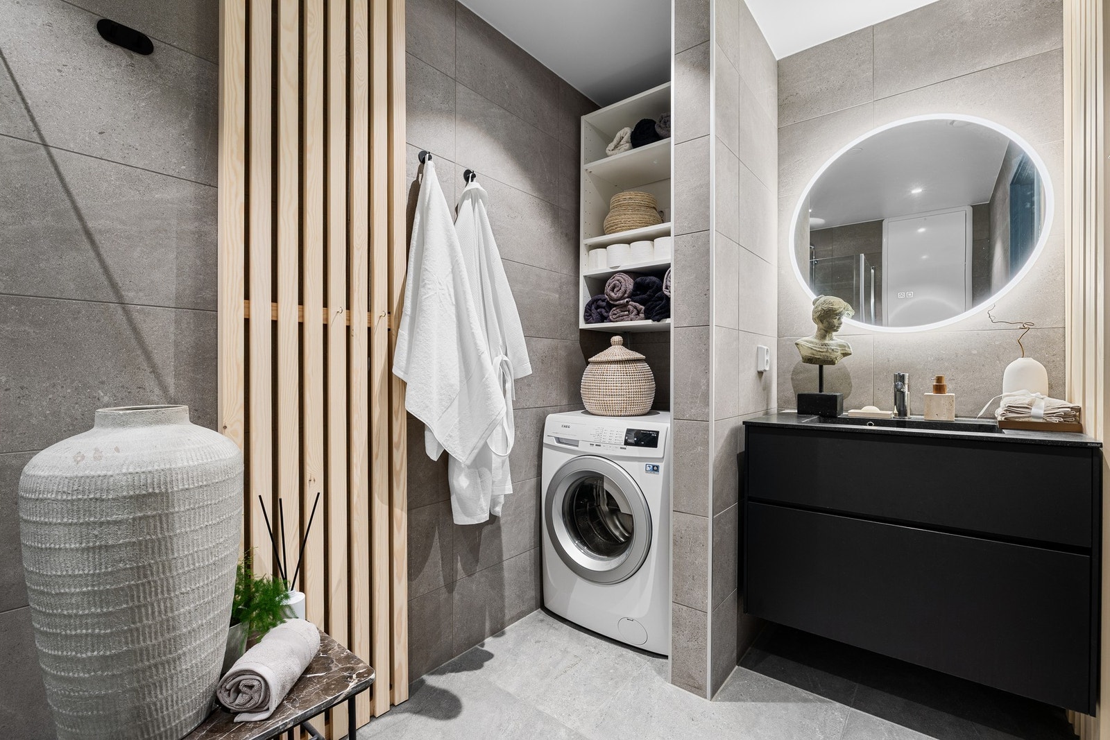 Legg merke til halvveggen på badet som gir en tydelig og praktisk inndeling. Perfekt til plassering av vaskemaskin og eventuelt en tørketrommel. I tillegg er det oppført nytt servantskap og speil på badet. Galleribilde