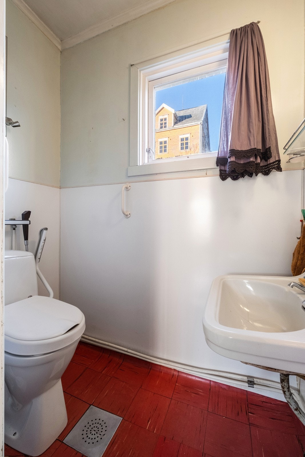 Enkelt bad i hovedetasjen med wc, dusj montert på vegg og en enkel servant. Galleribilde