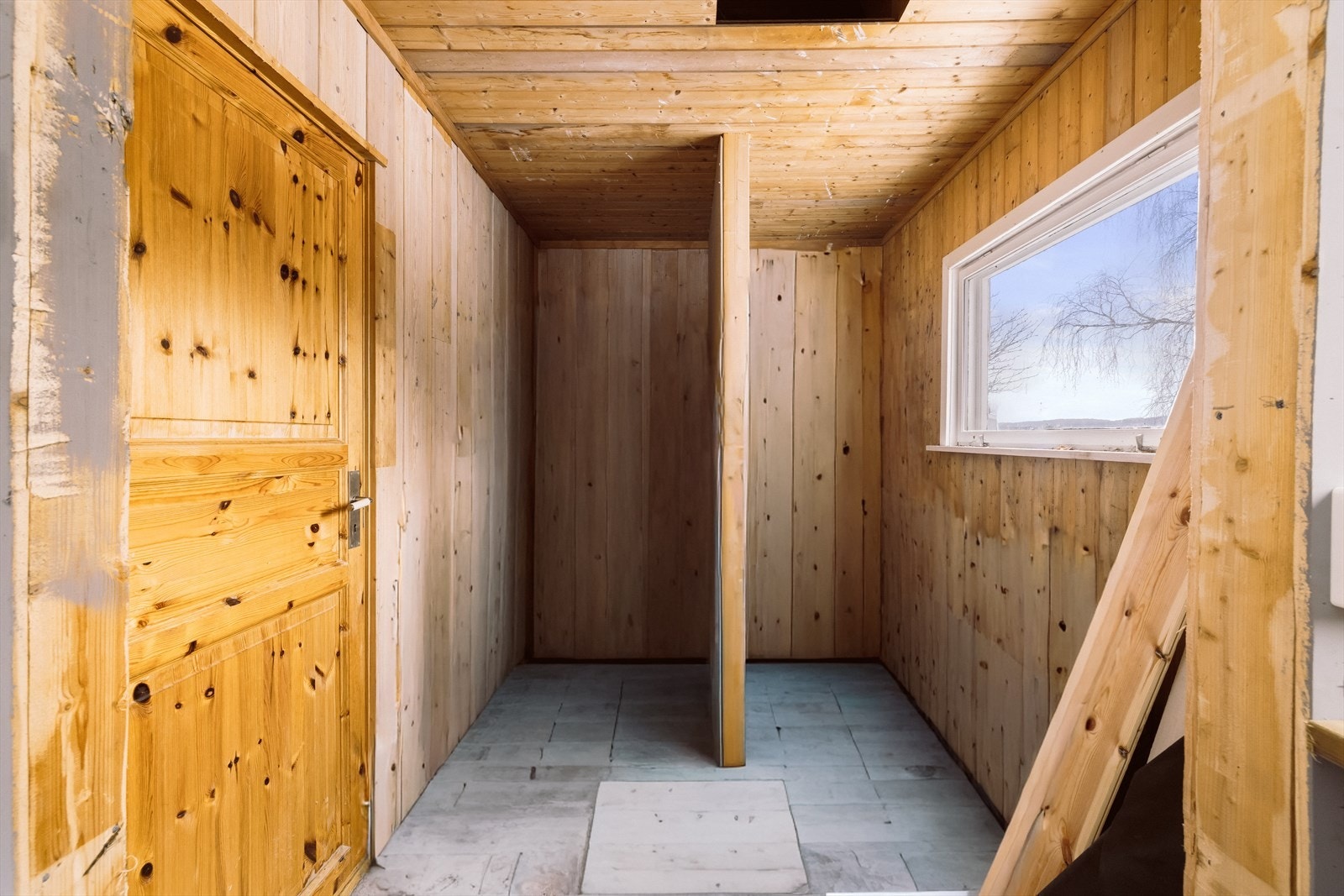 Rommet har panelte vegger og tak, med et vindu som slipper inn naturlig lys. (Digitalt renovert) Galleribilde