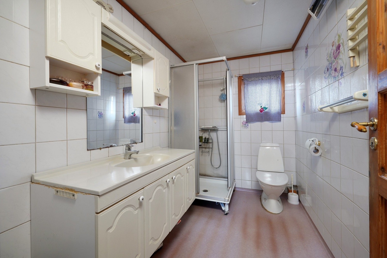 Bad i første etasje med flislagte vegger, dusjkabinett og servant med underskap. Galleribilde