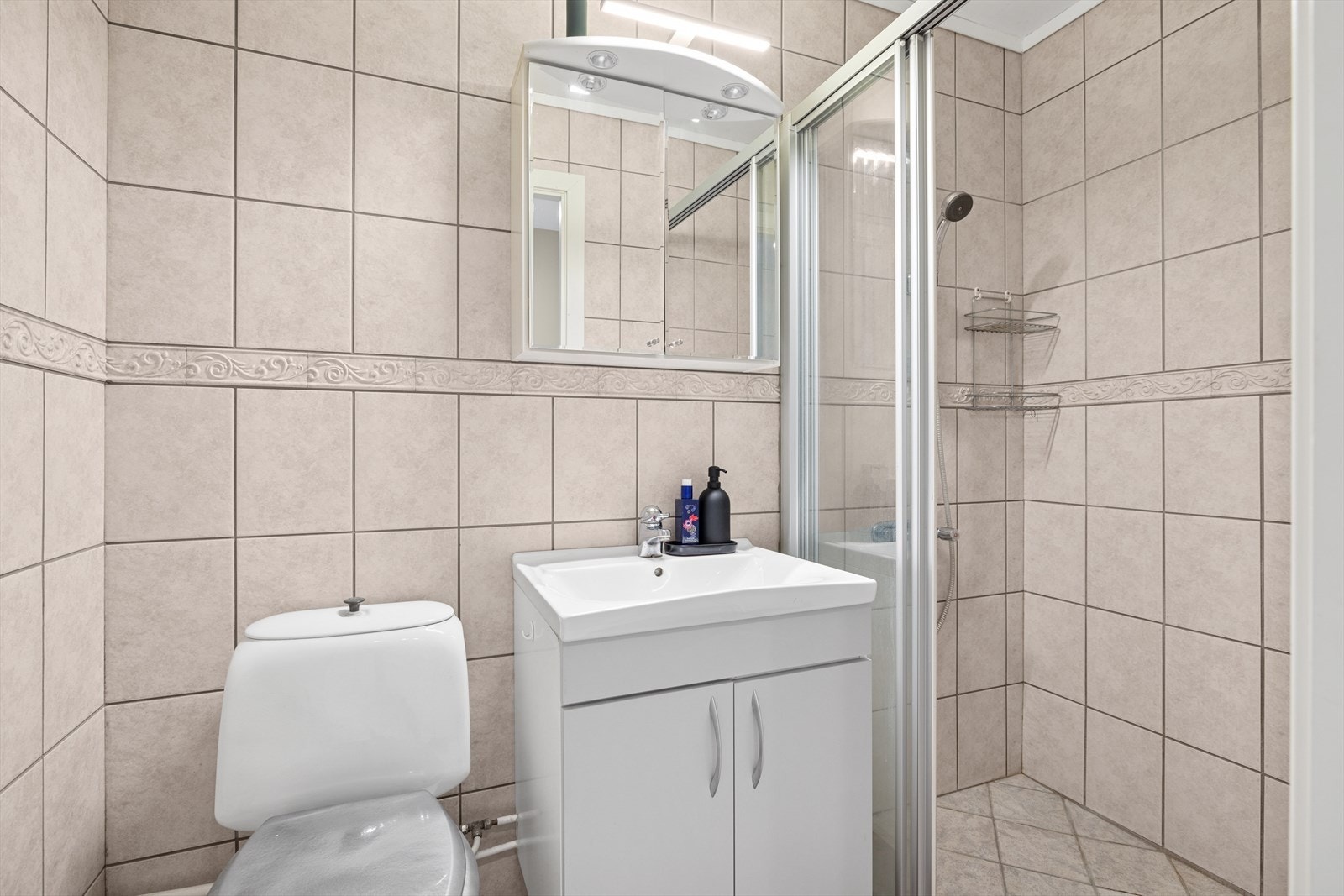 Flislagt bad med dusj, toalett, servantskap og speilskap Galleribilde