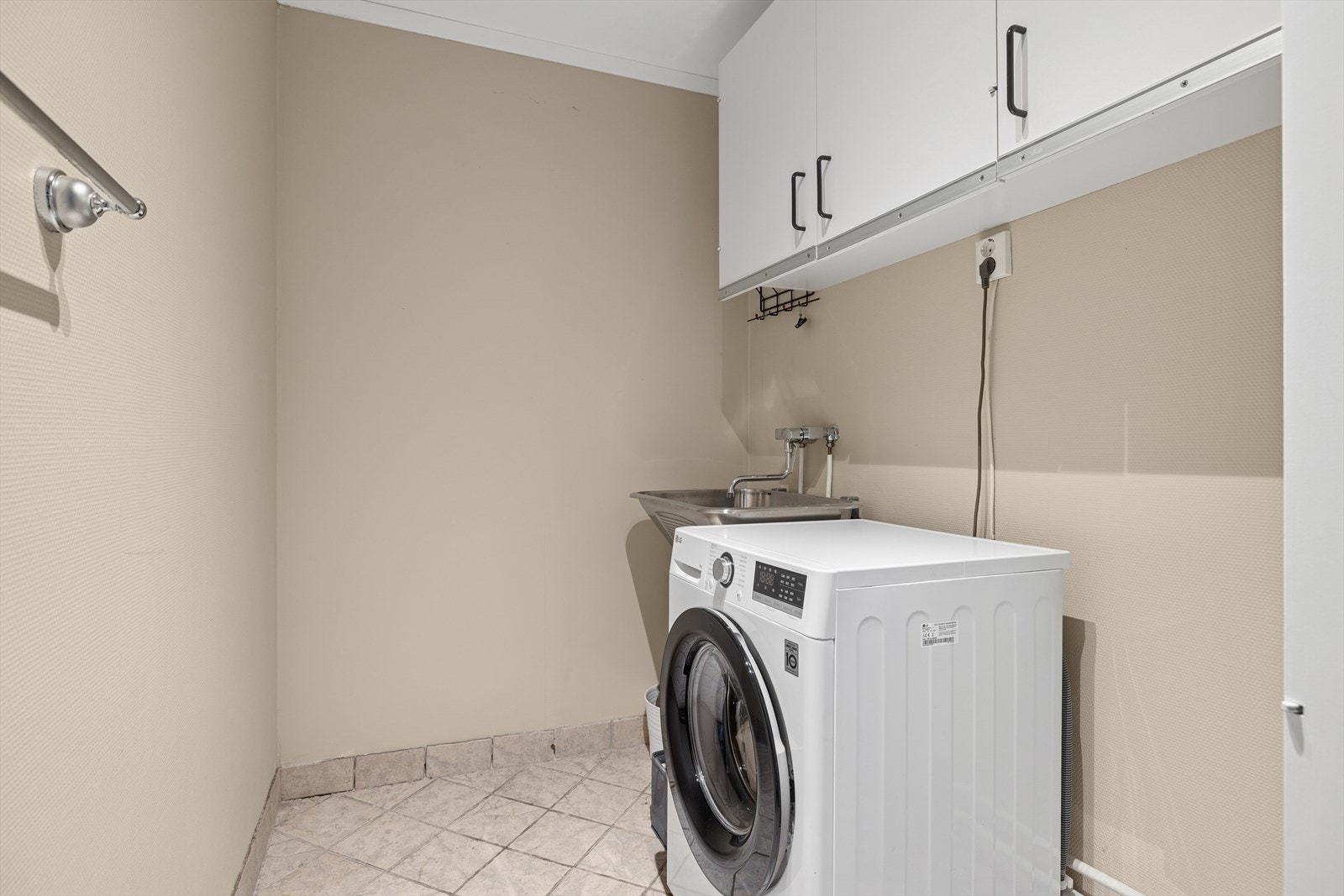 Vaskerom med stål vaskekar, veggskap og god plass til vaskemaskin Galleribilde