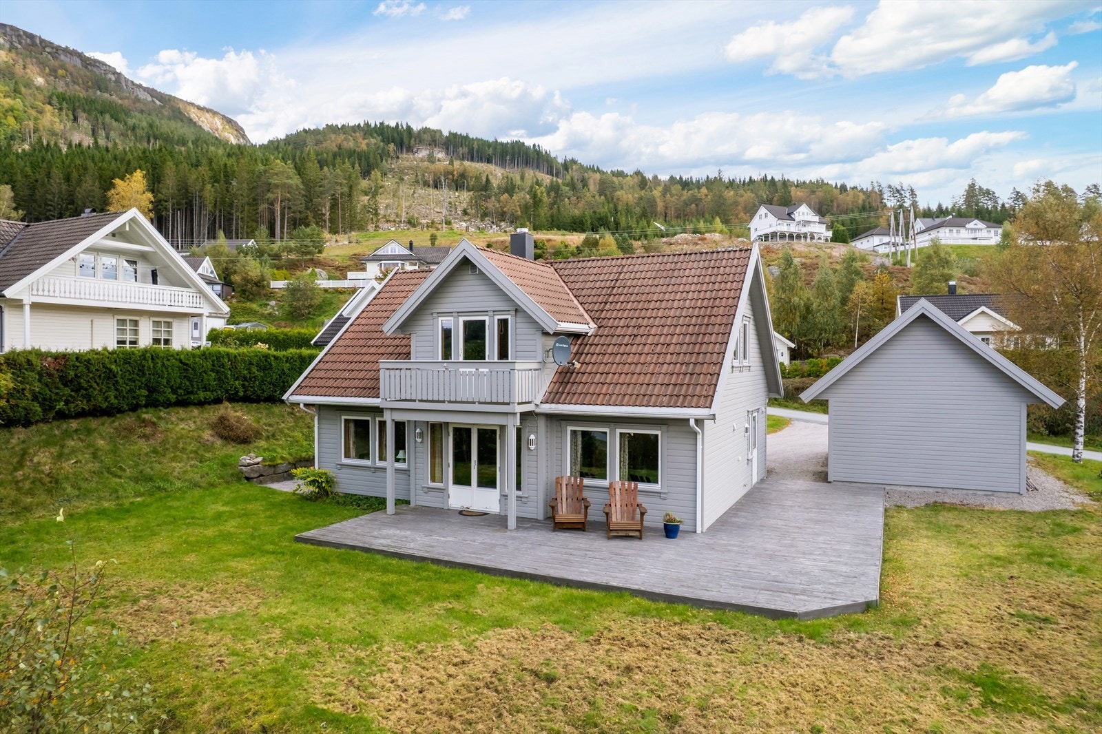 Tomten er pent opparbeidet med plen og trær som skaper et trivelig uteområde Galleribilde