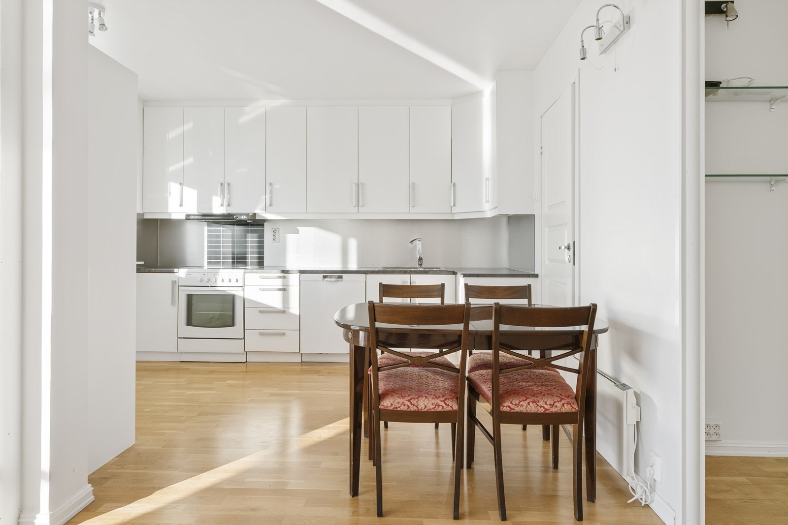 Kjøkkeninnredningen har hvite, glatte fronter og benkeplate av laminat. Innredningen er av eldre dato, men fronter og benkeplate ble byttet i 2013. Galleribilde