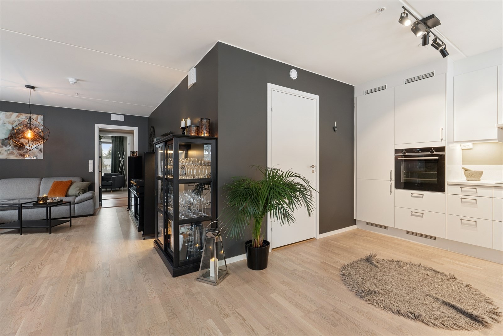 Kjøkkenet fremstår moderne og stilrent, med glatte fronter som gir et tidløst uttrykk. Den laminert benkeplaten med nedfelt kum og integrert koketopp gir både funksjonalitet og et ryddig, elegant preg. Galleribilde