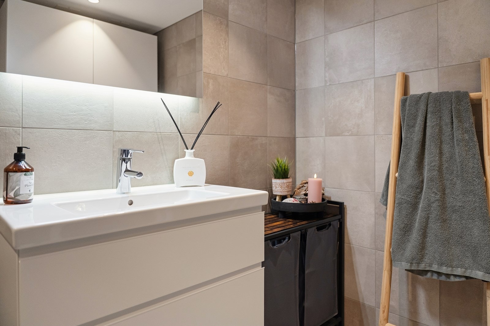 Innredningen består av en servantseksjon med nedfelt vask, et veggmontert toalett og et dusjhjørne med dusjvegger. Galleribilde