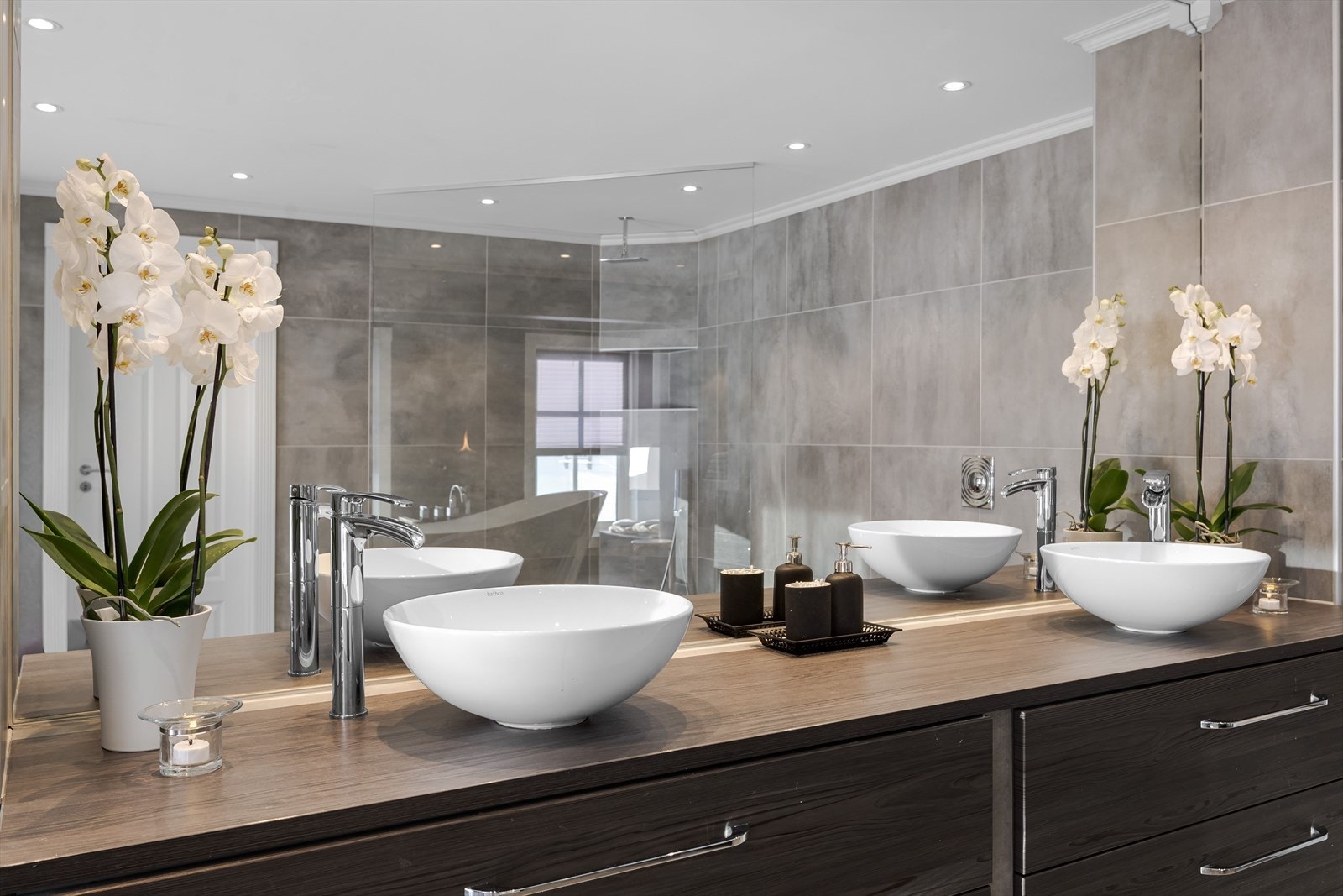 Pen baderomsinnredning med store skuffer og benkeplate med to ovenpåliggende bolleservanter, tilpasset heldekkende speil over. Galleribilde