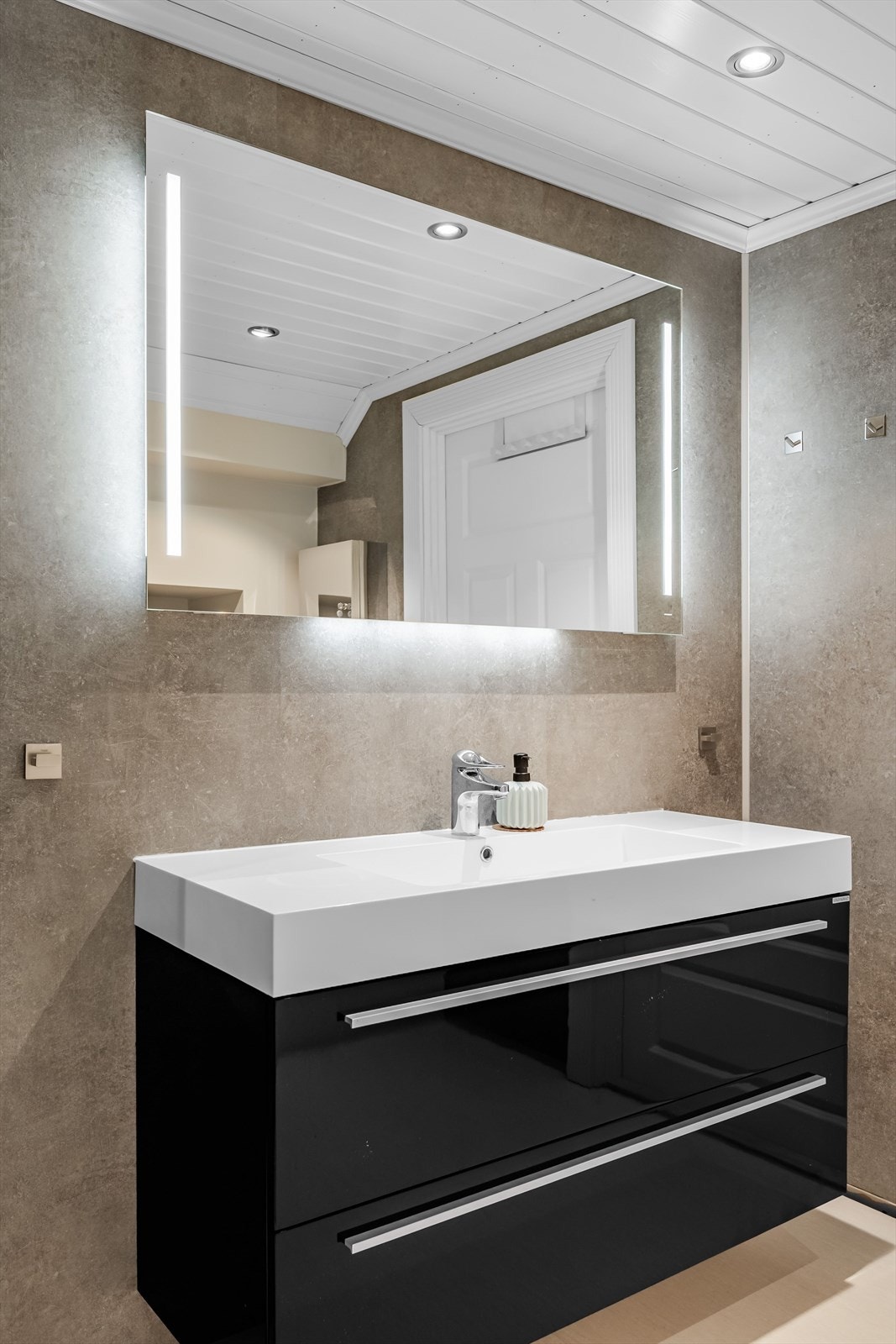 Baderommet er utstyrt med moderne innredning, speil med integrert belysning, dusjkabinett og vegghengt toalett. Galleribilde