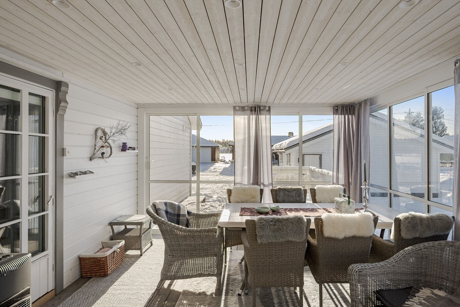 Sommerstuen har terrassebord på gulv, innfelte downlights i himlingen og skyvedører av glass som ble montert i 2025. Galleribilde