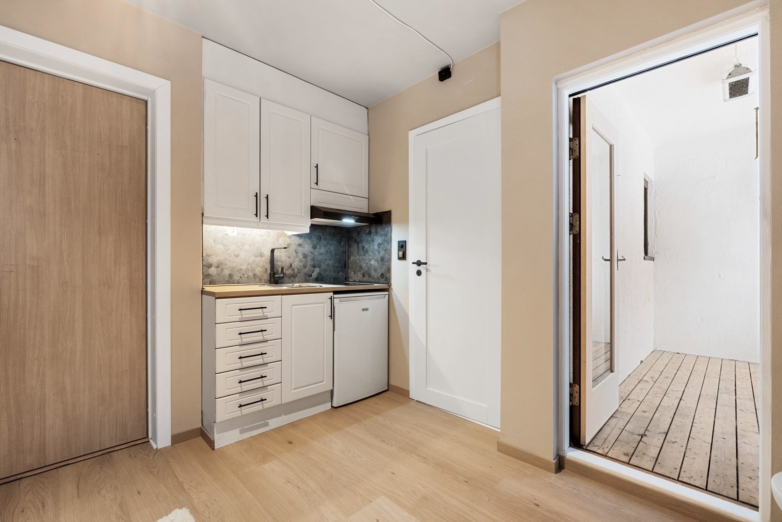 Hybelkjøkken med innredning fra 2012. Profilerte, hvite fronter og en benkeplate i laminat. Galleribilde