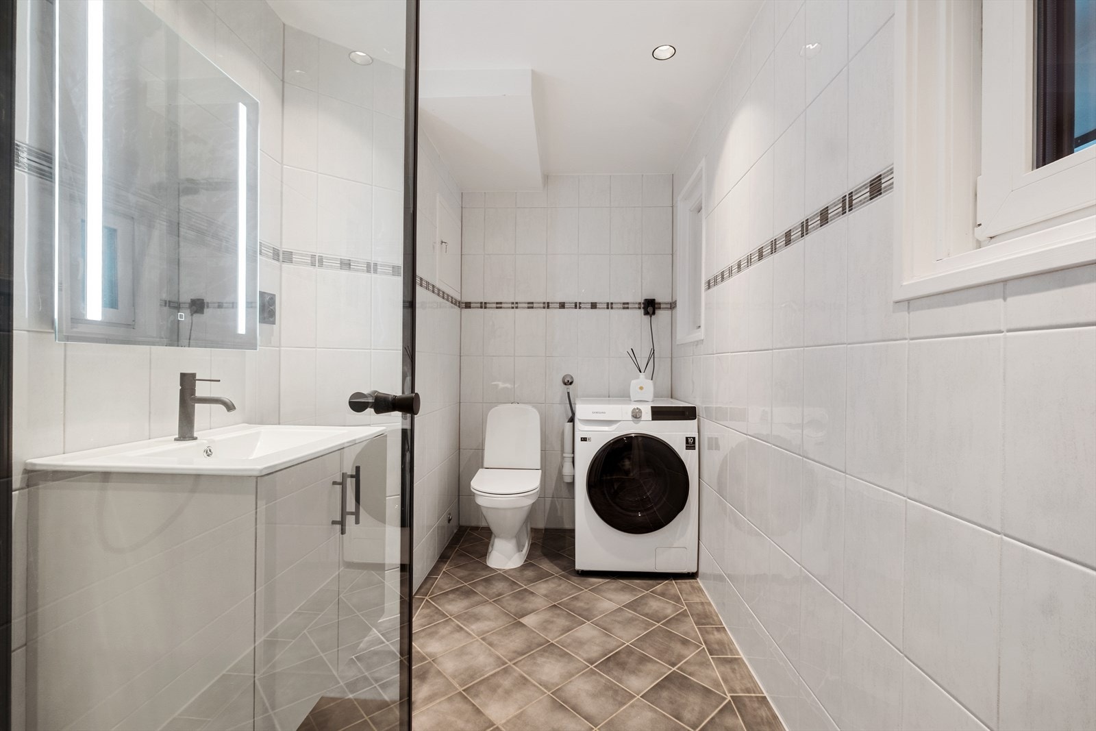 Bad/vaskerom fra 2012, er flislagt på gulv og vegger, med malt himling med downlights. Gulvet er utstyrt med elektriske varmekabler. Galleribilde