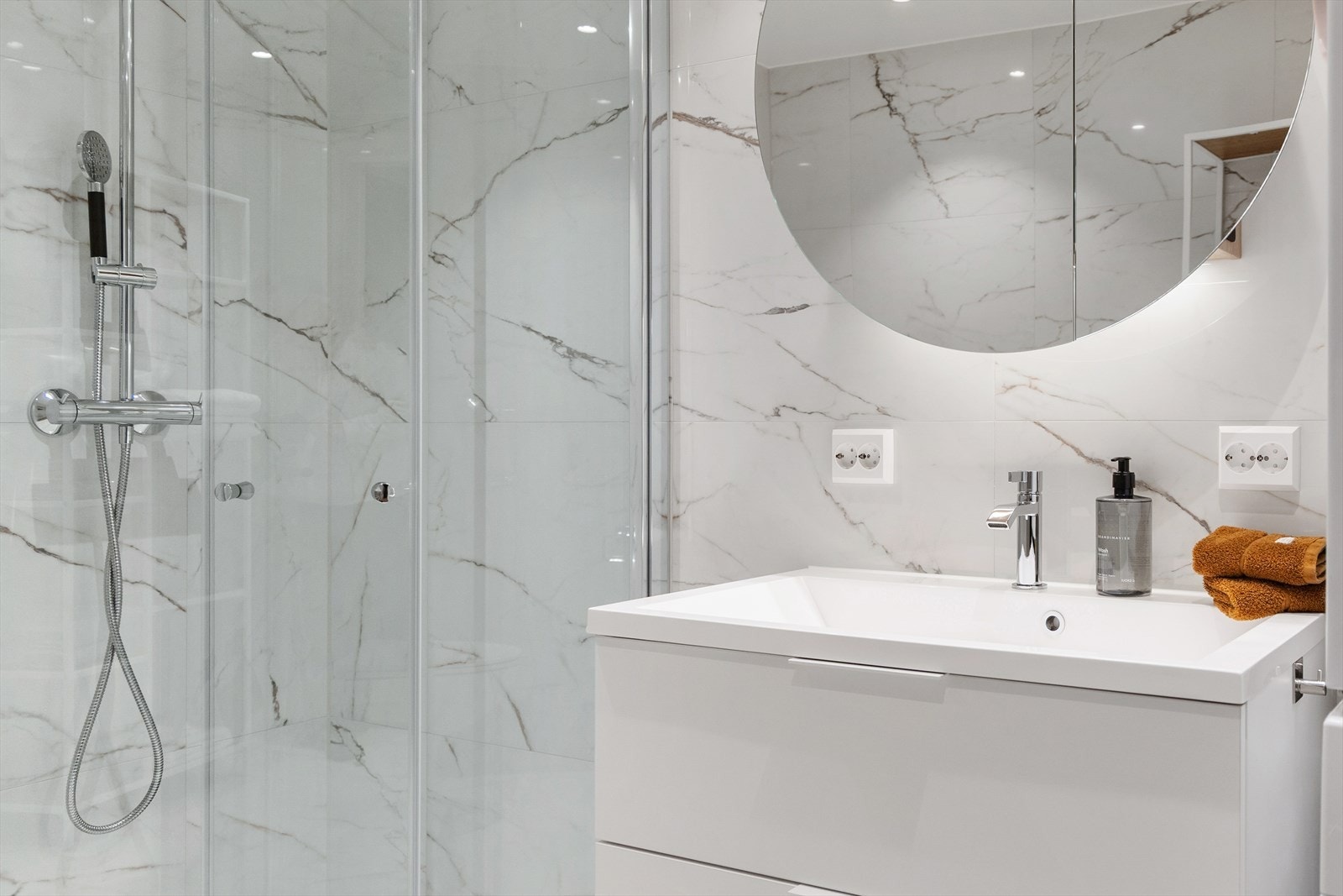 Innredningen består av speil med belysning, servant med tilhørende seksjon, dusjhjørne og veggmontert toalett. Galleribilde