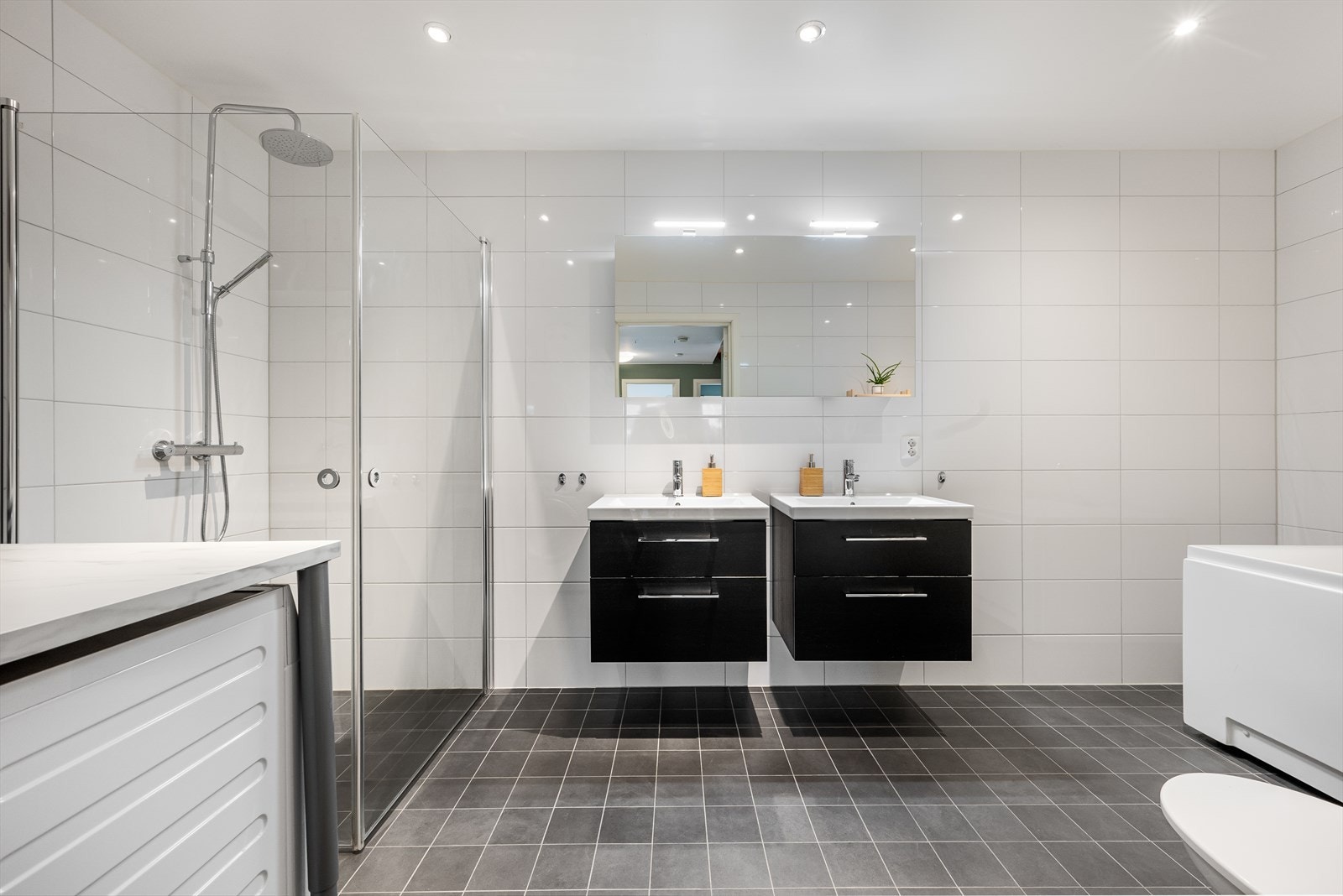 Stort, flislagt bad med dobbel vask, badekar, dusj, toalett og god plass til vaskemaskin/tørketrommel. Galleribilde