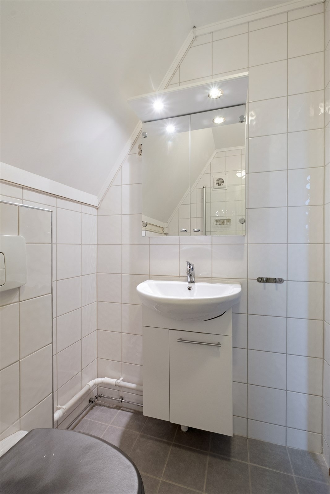 Baderom er utstyrt med servantskap, vegghengt toalett, opplegg for vaskemaskin og dusjhjørne med glassdører. Galleribilde