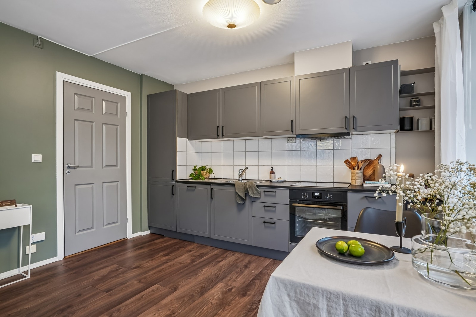 Praktisk utformet kjøkkeninnredning med mørke profilerte fronter og laminat benkeplate. Galleribilde