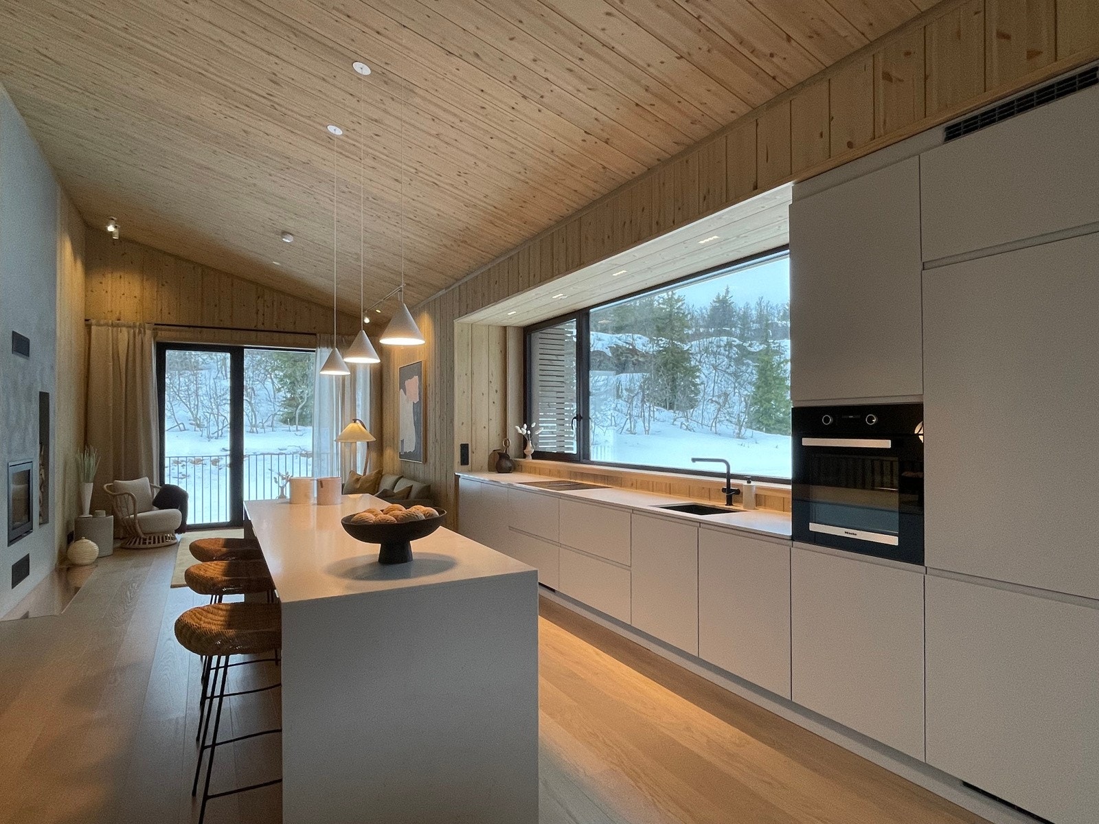 Prisbelønnede R21 arkitekter har tegnet bygningsvolumer som skiller seg ut i form, farge, materialitet og innhold. Kjøkken med skreddersydd innredning, integrerte hvitevarer og et generøst kjøkkenvindu.Bilde av lik hytte på annen beliggenhet i prosjektet. Galleribilde