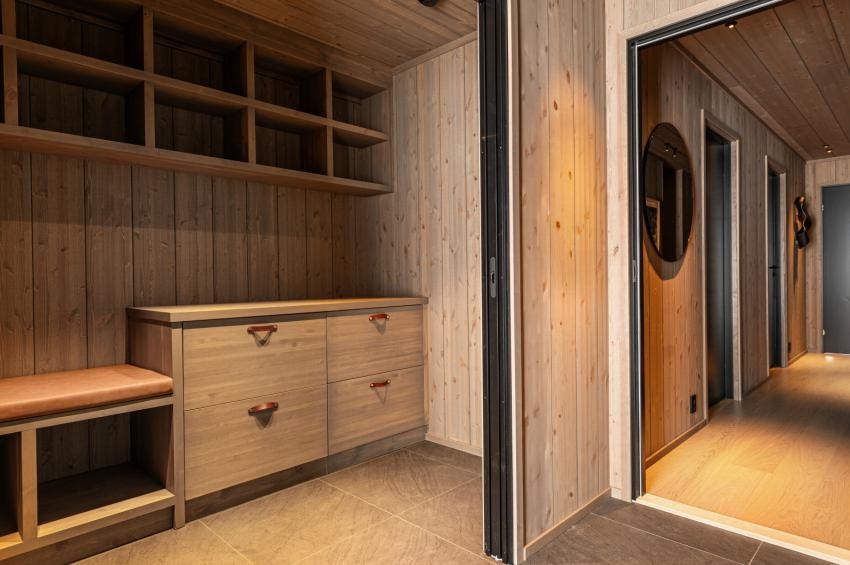 Mellom entréen og sportsboden er det doble skyvedører. Sportsboden i åpen posisjon gir et stort og praktisk omkledningsareal og plass til å preparere ski. Bilde fra en ferdigstilt (speilvendt) enhet i prosjektet. Galleribilde