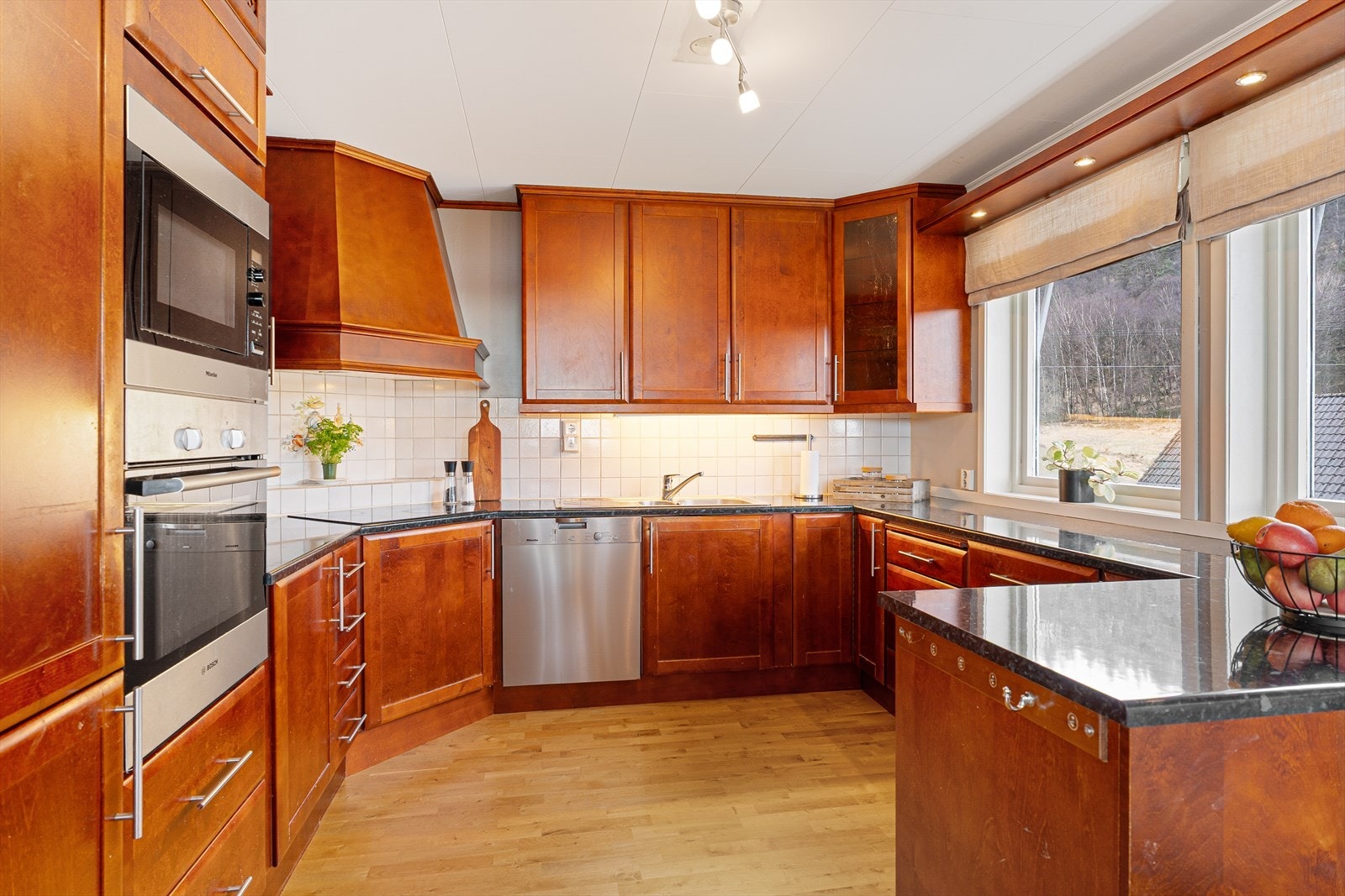 Kjøkken med kirsebær fronter og steinaktig benkeplate i laminat. Galleribilde