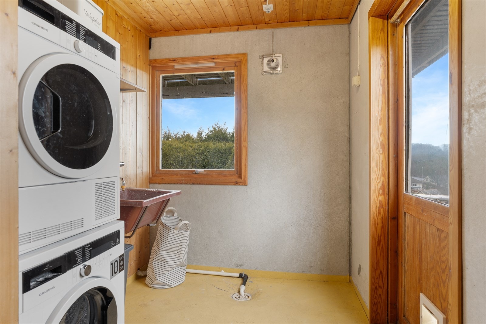 Det er vaskerom med malt betonggulv, panel på vegg og tak. Utslagsvask, opplegg for vaskemaskin og plass til tørketrommel. Galleribilde