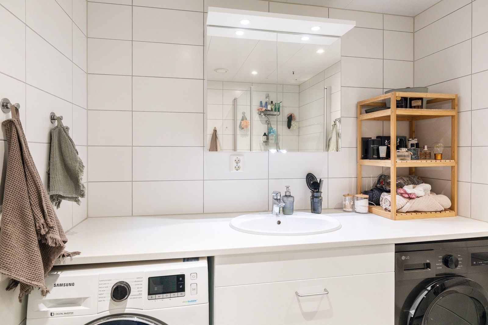 Plasstilpasset baderomsinnredning med nisjer for vaskemaskin og tørketrommel. Galleribilde