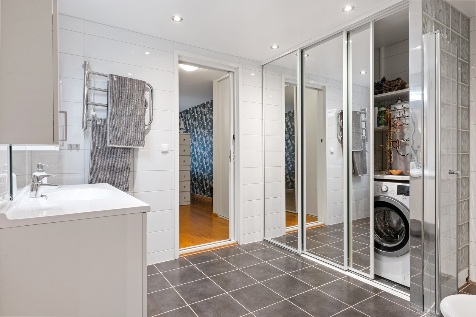 Stort bad hvor det er opplegg for vaskemaskin inne bak skyvedører Galleribilde