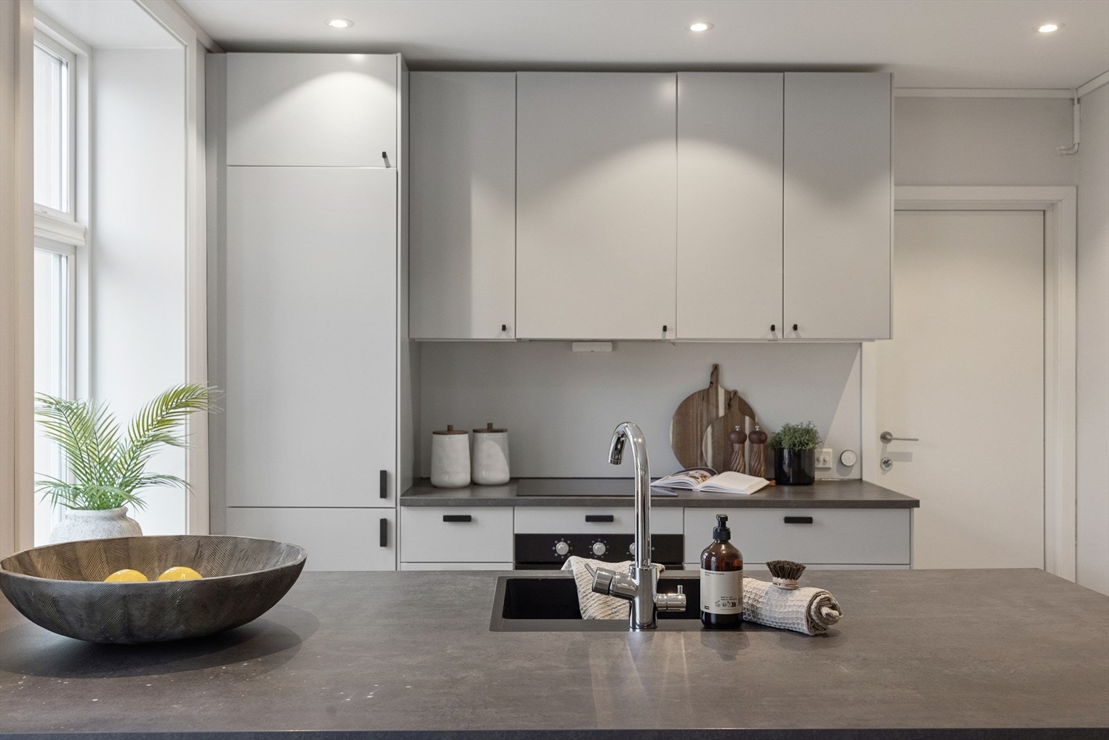 Pen og solid kjøkkeninnredning med integrerte hvitevarer. Her er det god skap- og benkeplass. Galleribilde