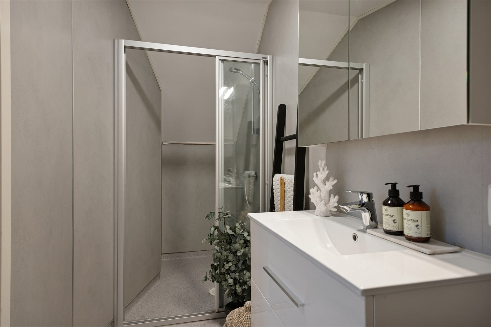 Baderommet måler 4,2 kvm. Dusjvegger av glass og dusjgarnityr på vegg, vegghengt toalett og innredning med servant. Galleribilde