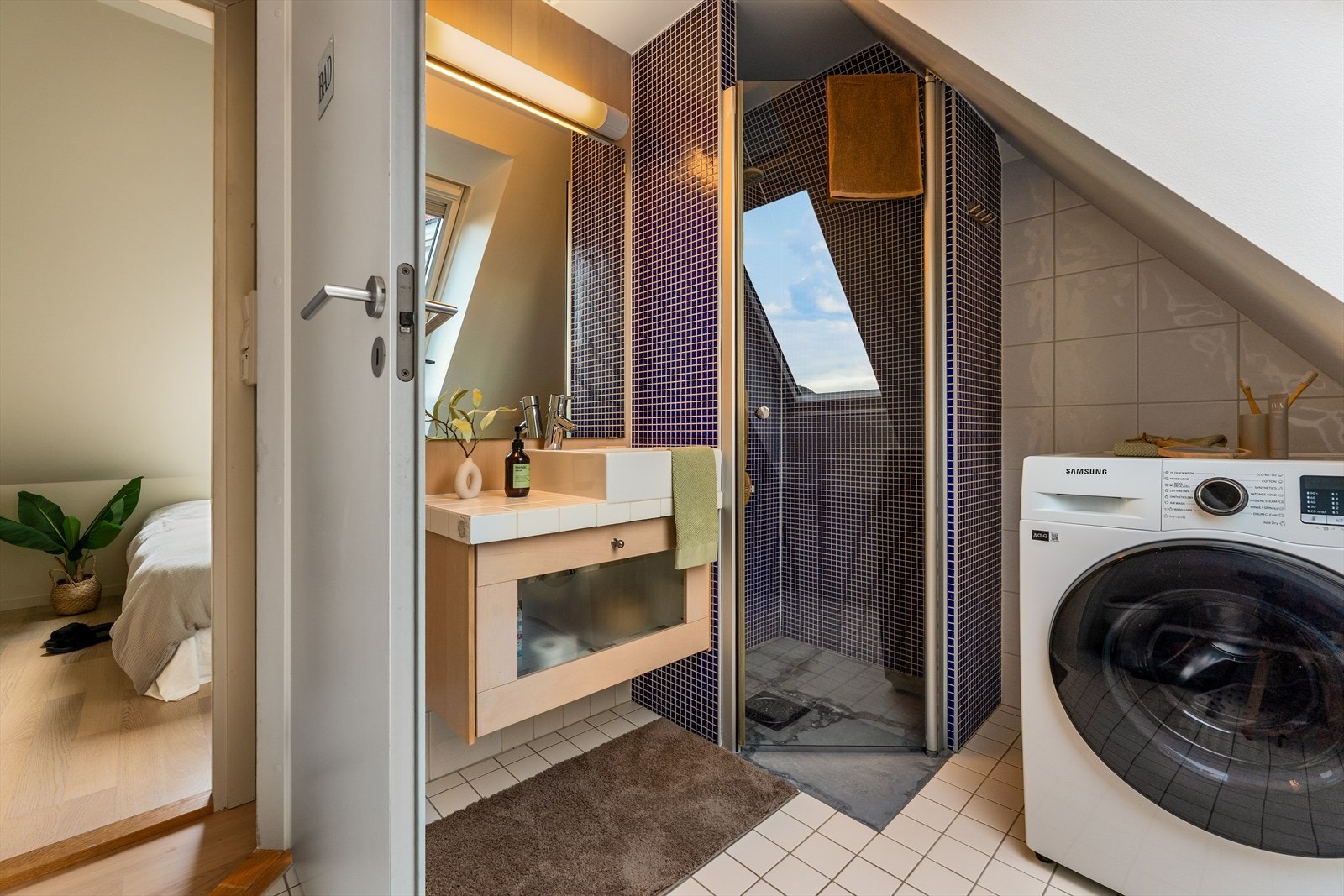 Badet har fliser og moderne microsement på gulvet, kombinert med termostatstyrte varmekabler som gir en behagelig varme året rundt. Veggene er kledd med stilrene fliser som gir et rent og tidløst uttrykk Galleribilde