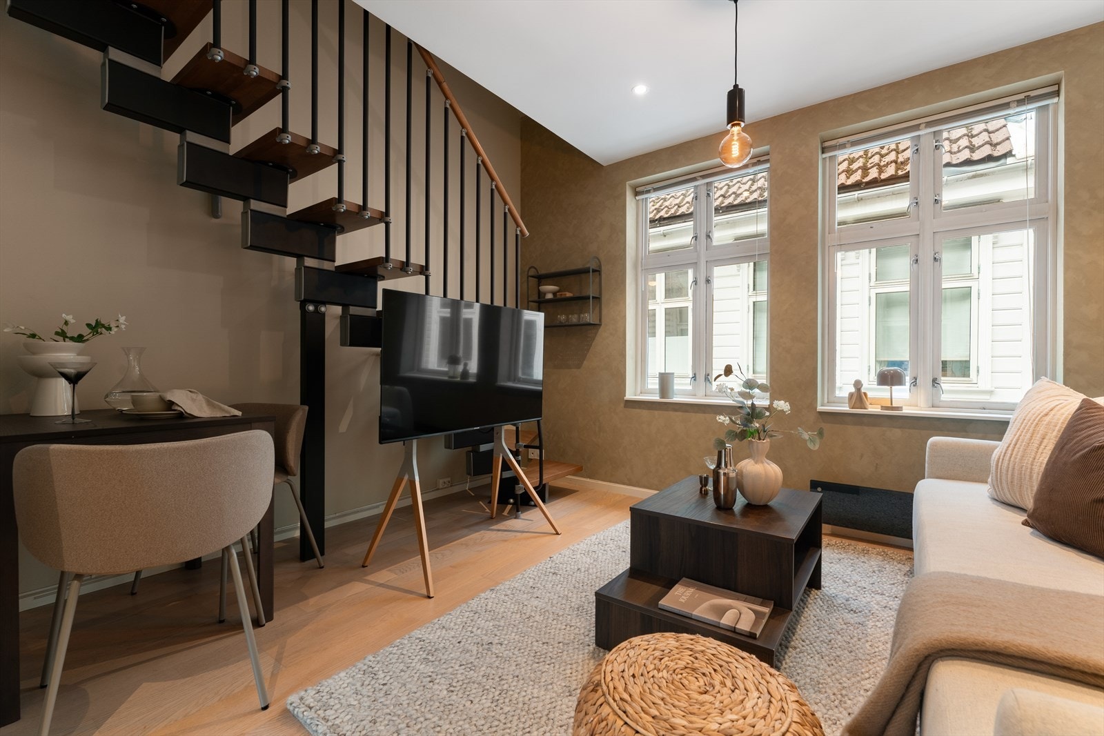 Den moderne trappeløsningen fungerer som et elegant blikkfang og tilfører rommet et moderne preg som løfter helhetsinntrykket av boligen. Stuen byr på naturlige møbleringssoner for både spisebord og sofagruppe Galleribilde